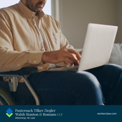 A disabled man in a wheelchair working on a laptop